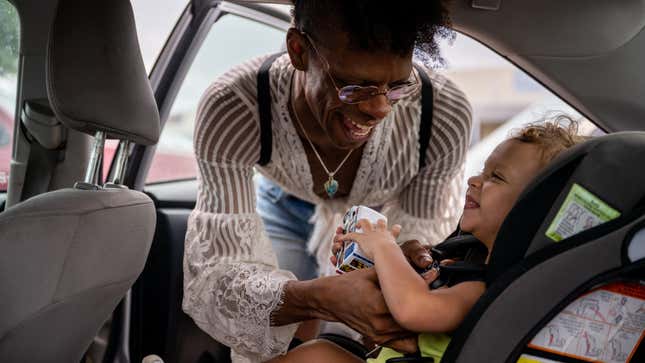 A person buckling a child into a car seat