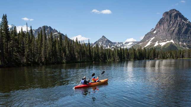 Couple in tandem kayak floating through beautiful mountain scenery