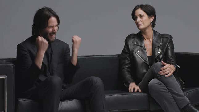 Keanu Reeves fist pumps in joy as Carrie Anne-Moss looks on, far less amused by it all. 