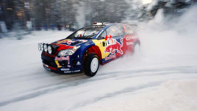 A photo of a Red Bull-branded rally car driving on snow. 