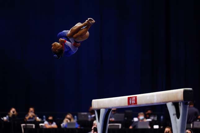 Simone Biles tucks into a twist as she dismounts a balance beam.