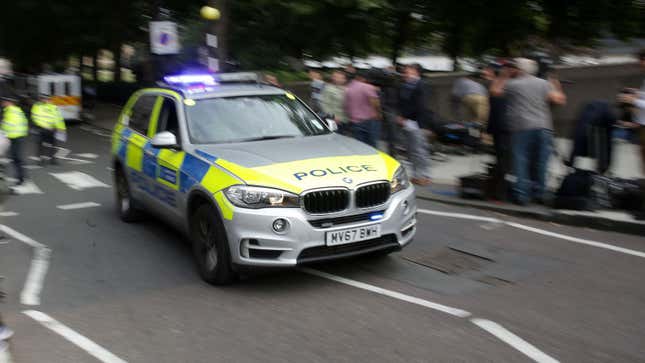 A police BMW X5 passes a crowd.