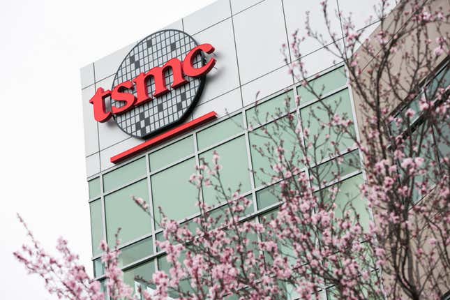 TSMC logo on corner of windowed office building with a tree with pink flowers in the foreground