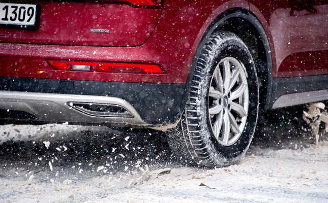 A close-up of the rear wheel of a red Audi SUV in the snow