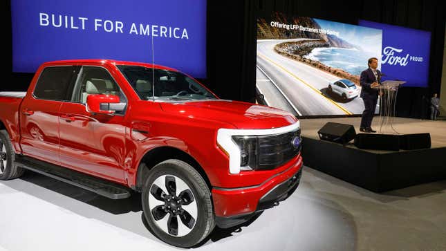 Ford CEO Jim Farley announcing a new battery plant next to a red Ford F-150 Lightning