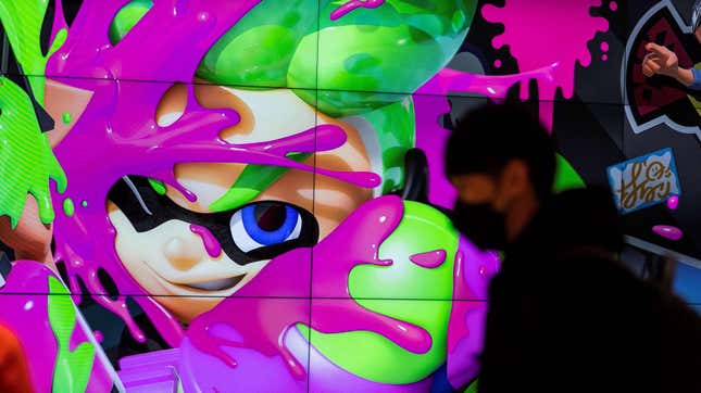 شخص يرتدي قناع وجه يمر عبر شاشة تعرض شخصيات لعبة نينتندو "ملعقة" في متجر لشركة الألعاب اليابانية العملاقة نينتندو في طوكيو
