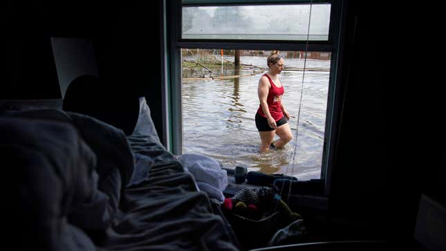 A woman, seen through the window, walks through floodwaters beside her flood-damaged home in the aftermath of Hurricane Ida in Louisiana.