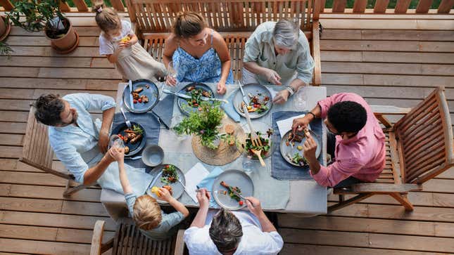 Family on vacation eating dinner on deck in summertime