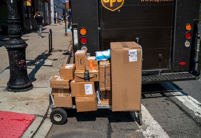 A cart full of packages is sitting behind a parked UPS truck