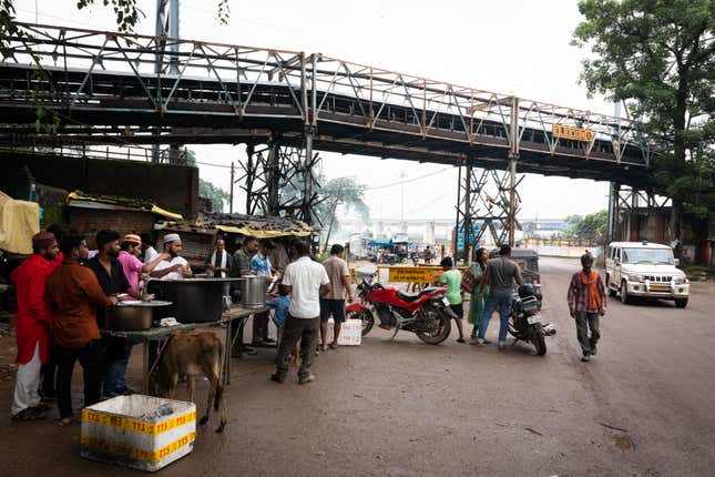 Muslims offer free food to passers-by on the occasion of Muharram—one of four sacred months in Islamic calendar. Above them, an open-air conveyor belt carries coal to the Hasdeo Thermal Power Station in Darri near Korba.