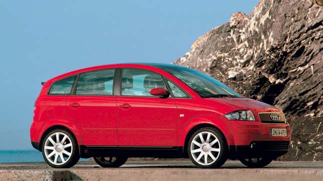 A red Audi A2 parked in front of a cliff from the side view