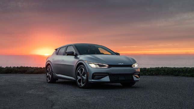 A photo of a silver Kia EV6 taken with the sun setting behind. 