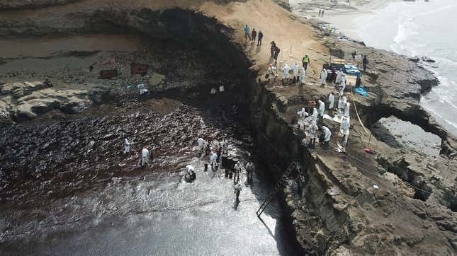 Cleaning crews working to remove oil from a beach off the summer resort town of Ancon, northern Lima, on January 22, 2022.