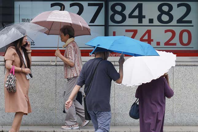 People walk in the rain in front of an electronic stock board showing Japan&#39;s Nikkei 225 index at a securities firm Monday, Sept. 4, 2023, in Tokyo. Stocks were higher in Asia on Monday after Wall Street was boosted by a report that signaled the US jobs market, while still healthy, is showing some signs of cooling. (AP Photo/Eugene Hoshiko)