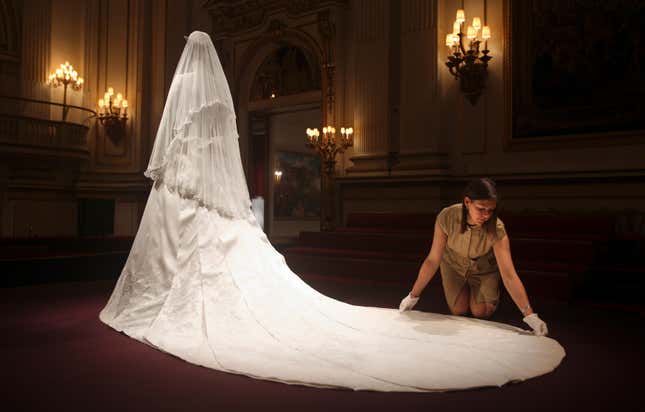 Exhibition curator, Caroline de Guitaut, adjusts the wedding dress of Britain's Catherine, Duchess of Cambridge, at Buckingham Palace in London July 20, 2011. Buckingham Palace expects record crowds this summer as up to 650,000 people are set to file into Queen Elizabeth's London residence and past the dress worn by Kate Middleton at her royal wedding to Prince William. The ivory and white garment, designed by Sarah Burton for Alexander McQueen, won over the fashion press and public when Middleton, now the Duchess of Cambridge and a future queen, walked up the aisle of Westminster Abbey in April. Picture taken July 20, 2011. REUTERS/Lewis Whyld/Pool (BRITAIN - Tags: ROYALS TRAVEL SOCIETY ENTERTAINMENT) - GM1E77M067A01