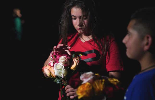 A young girl holds flowers outside the Willie de Leon Civic Center, where people gather to mourn in Uvalde, Texas, on May 24, 2022. 