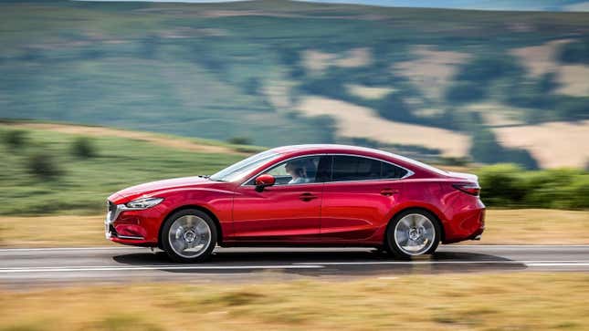 Un Mazda6 rojo conduciendo por una carretera