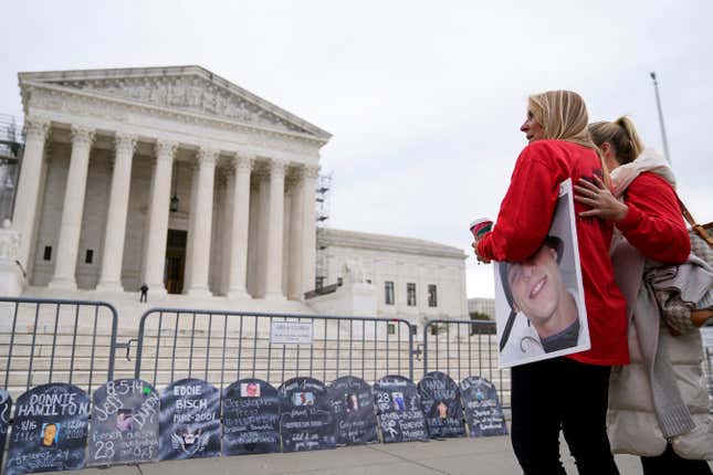 Jen Trejo holds a photo of her son Christopher as she is comforted outside the Supreme Court Monday, Dec. 4, 2023, in Washington. Her son was 32 when he died and she said about Purdue Pharma and the Sackler family, &quot;You can&#39;t just kill my child and just pay a fine.&quot; The Supreme Court is wrestling with a nationwide settlement with OxyContin maker Purdue Pharma that would shield members of the Sackler family who own the company from civil lawsuits over the toll of opioids. (AP Photo/Stephanie Scarbrough)