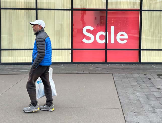 A shopper passes by a sign trumpeting a sale at a clothing store in the Thornton Premium Outlets Monday, Dec. 18, 2023, in Thornton, Colo. On Wednesday, the Conference Board reports on U.S. consumer confidence for December. (AP Photo/David Zalubowski)