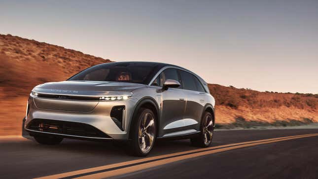 A silver lucid gravity driving on a desert road