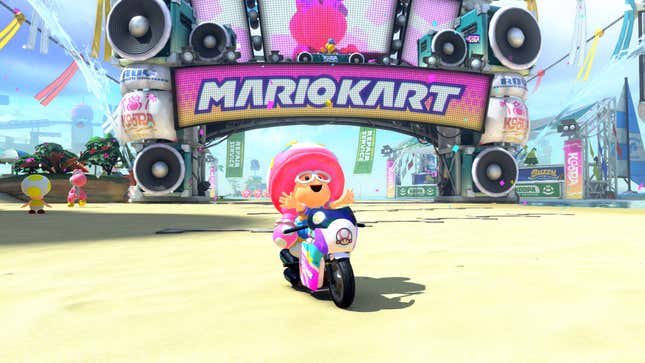 A character sits on a motorcycle right in front of the finish line for a Mario Kart track.