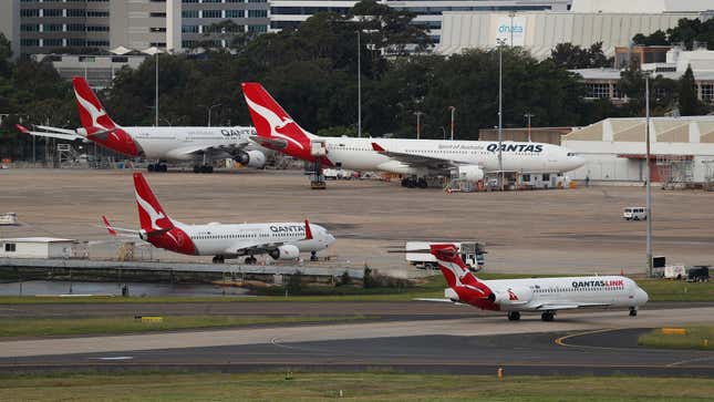 Un avion exploité par la compagnie aérienne régionale QantasLink de Qantas Airways Ltd., au premier plan, taxi alors que d'autres avions Qantas sont stationnés à l'aéroport de Sydney, en Australie, le mardi 17 mars 2020.