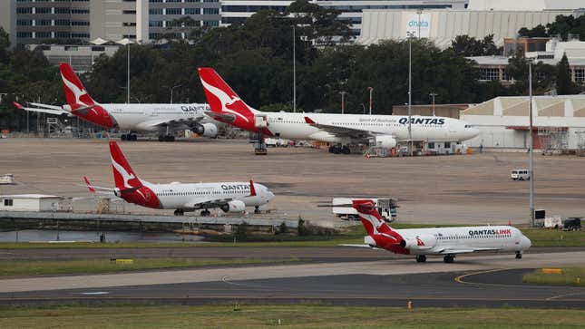 An aircraft operated by Qantas Airways Ltd.'s regional airline QantasLink, foreground, taxis as other Qantas aircraft stand parked at Sydney Airport in Sydney, Australia, on Tuesday, March 17, 2020.