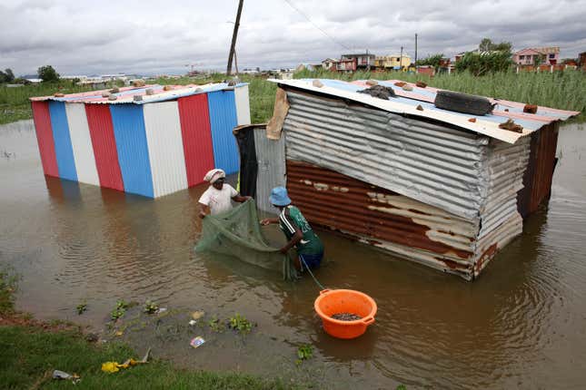 People use a net to catch fish around their flooded dwelling in Antananarivo, Madagascar, Monday, Jan. 24.