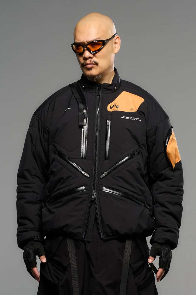 1) Sleek limited edition Death Stranding 2 jacket displayed on a bust2) Close-up of the high-quality stitches and fabric of the Death Stranding 2 jacket3) Detailed view of the unique Death Stranding 2 logo on the jacket 4) Lifestyle shot of a model posing in the stylish Death Stranding 2 jacket 5) New Death Stranding 2 jacket paired with matching game accessories.6) Hero shot of the Death Stranding 2 jacket, highlighting its exclusive design.