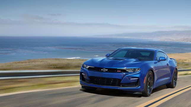 A photo of a blue Chevrolet Camaro on an ocean road. 