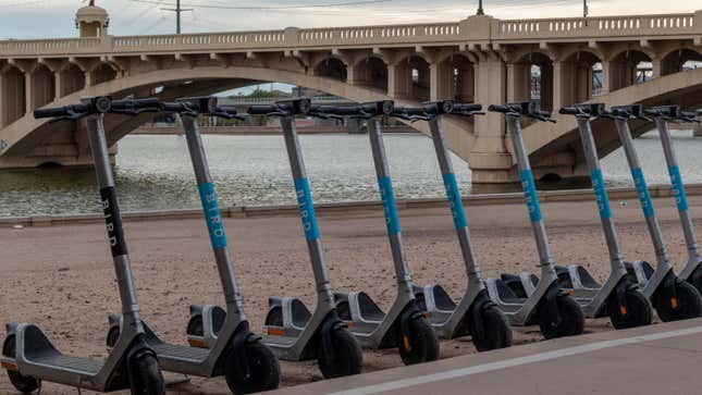 Row of Bird electric scooters ready for rental with Mill Ave. bridge in background