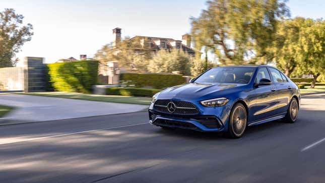 A photo of a blue Mercedes C Class sedan driving down a highway. 