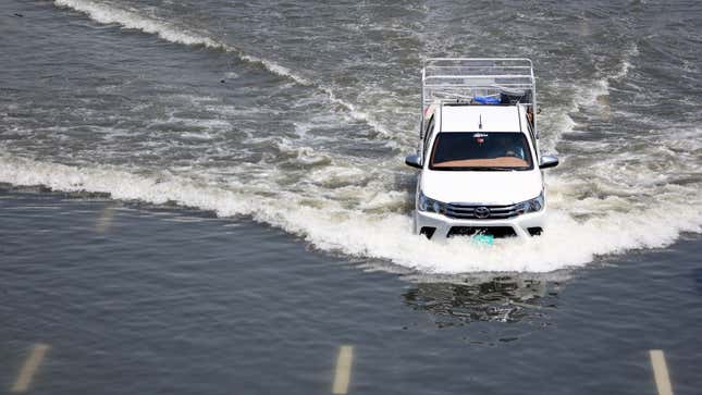 A photo of a car driving through flood water in Dubai. 