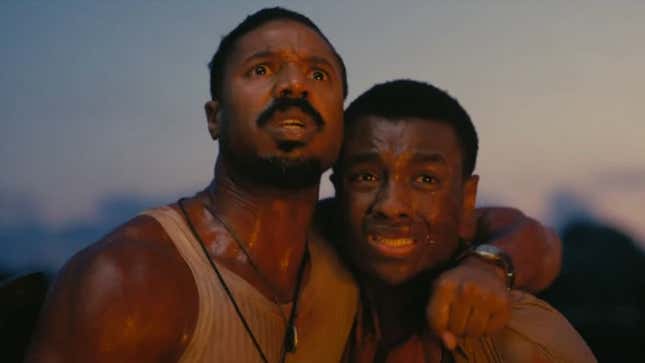 Michael B. Jordan puts his arm around another man, while staring scared at something above him.