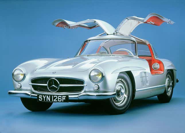 A studio shot of a silver '57 300SL Gullwing with the doors up and you can see parts of the bright red interior.