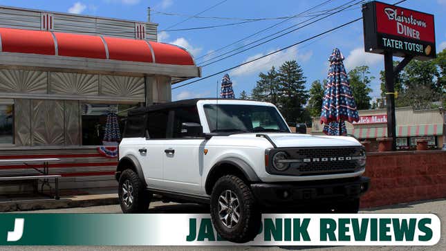 A photo of a white Ford Bronco in front of a diner. 