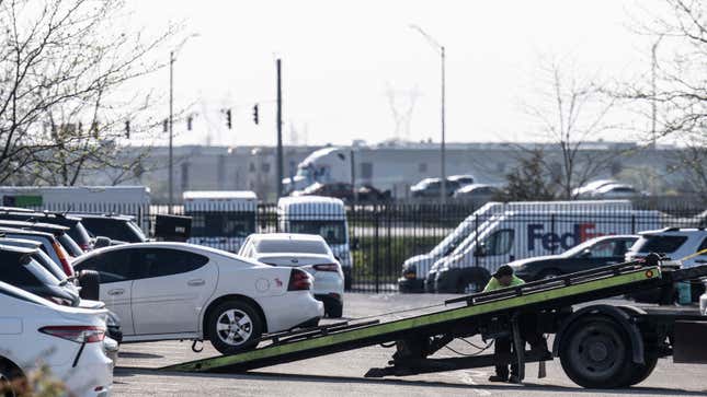 A tow truck hauls a car out a parking lot 