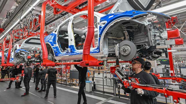 20 March 2023, Brandenburg, Grünheide: Employees of the Tesla Gigafactory Berlin Brandenburg work on a production line of a Model Y electric vehicle.