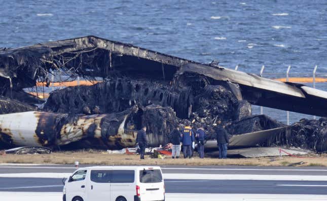 Police investigator look at the burn-out wreckage of Japan Airlines plane at Haneda airport on Thursday, Jan. 4, 2024, in Tokyo, Japan. A transcript of communication between traffic control and two aircraft that collided and burst into flames at Tokyo’s Haneda Airport showed that only the larger Japan Airlines passenger flight was given permission to use the runway where a coast guard plane was preparing for takeoff. (Kyodo News via AP)