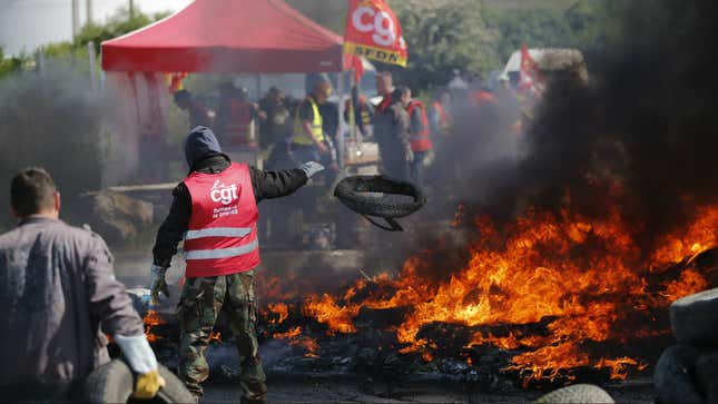 A protester throws a tyre onto a burning barricade in front of an oil depot in Donges.