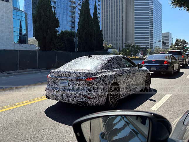 Rear 3/4 view of a camouflaged next-gen Audi S5 Sportback in traffic