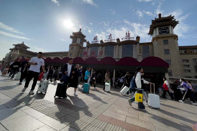 Travelers with their luggage arrive at Beijing Railway Station to catch their trains in Beijing, Friday, Sept. 29, 2023. Tens of millions of Chinese tourists are expected to travel within their country, splurging on hotels, tours, attractions and meals in a boost to the economy during the 8-day autumn holiday period that began Friday. (AP Photo/Andy Wong)