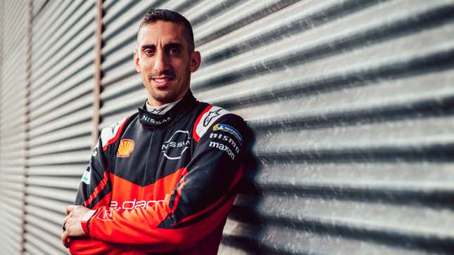 A photo of Nissan driver Sébastien Buemi leaning against a garage door. 