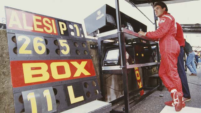 Jean Alesi of France stands in the pit lane in his red Ferrari fire suit. 