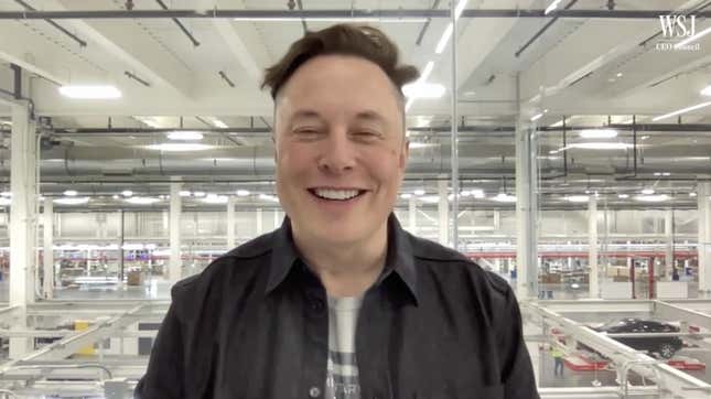 Elon Musk smiling in front of the floor of one of his battery factories.