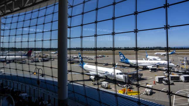 People sit in the central terminal looking out towards Alaska Airline planes at Seattle-Tacoma International Airport on June 19, 2024 in Seattle, Washington.