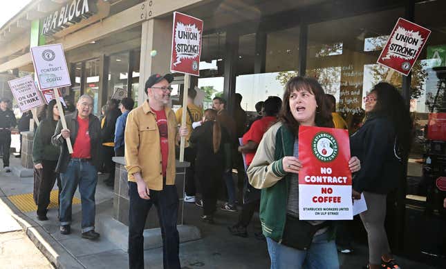 Starbucks-Mitarbeiter halten Schilder, während sie am 20. Dezember 2024 in Burbank, Kalifornien, während eines Streiks vor einer Starbucks-Filiale streiken, um Tarifverträge zu fordern. 