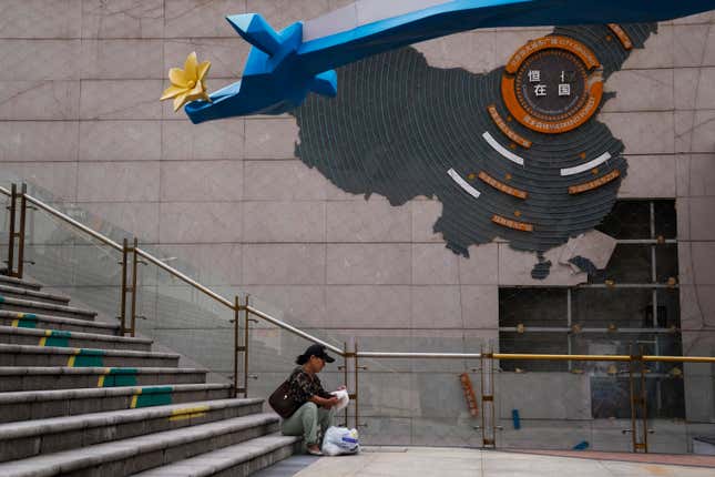 A woman sorts out her groceries near a map showing partially damaged Evergrande development projects in China, at an Evergrande city plaza in Beijing on Sept. 18, 2023. A Hong Kong court on Monday, Oct. 30 adjourned a winding up hearing for property developer China Evergrande Group&#39;s until Dec. 4. (AP Photo/Andy Wong)