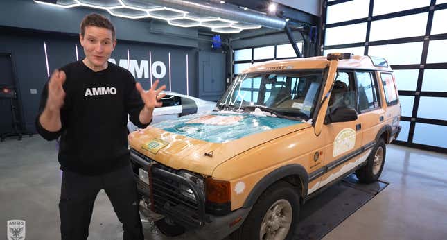 Larry Kosilla of Ammo NYC stands in front of a yellow Camel Trophy Land Rover Discovery