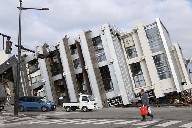 A man walks past a fallen building in Wajima, Ishikawa prefecture, Japan, Thursday, Jan. 11, 2024. A powerful earthquake slammed the western coastline of Japan on New Year’s Day. (Kyodo News via AP)